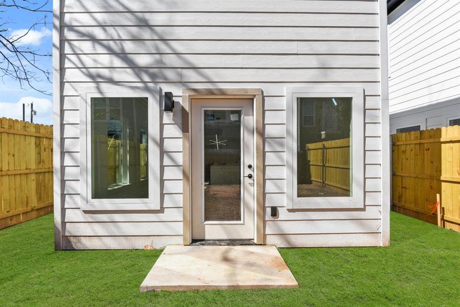 Property entrance with a lawn and fence