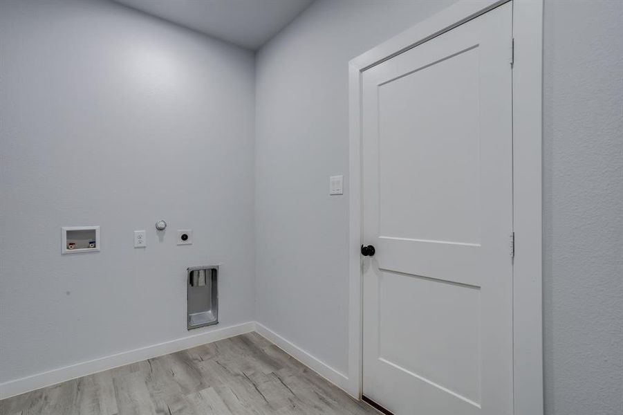 Washroom featuring light wood finished floors, hookup for a gas dryer, hookup for an electric dryer, and hookup for a washing machine Washroom featuring light wood finished floors, hookup for a gas dryer, hookup for an electric dryer, and hookup for a washing machine