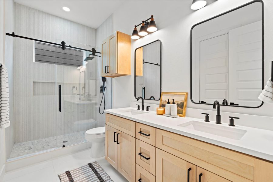The primary ensuite showcases a double vanity with maple cabinetry, matte black fixtures, and framed mirrors under designer lighting.