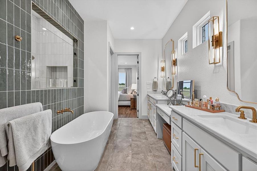 Spacious bathroom featuring a freestanding tub, a large walk-in shower with vertical subway tile, dual vanities with integrated sinks, and ample natural light from multiple windows