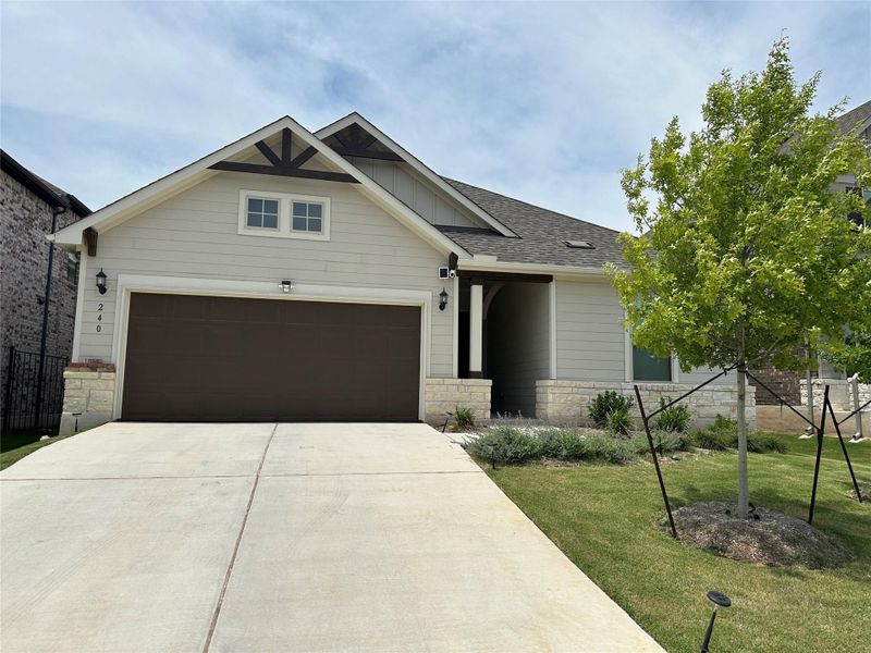Contemporary single-story residence featuring light-colored siding, a stone facade, and a dark brown garage door Contemporary single-story residence featuring light-colored siding, a stone facade, and a dark brown garage door