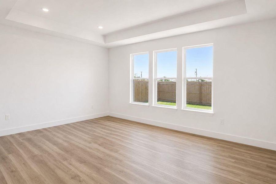 Recessed lighting and a tray ceiling add elegance to this inviting living space with wood flooring.