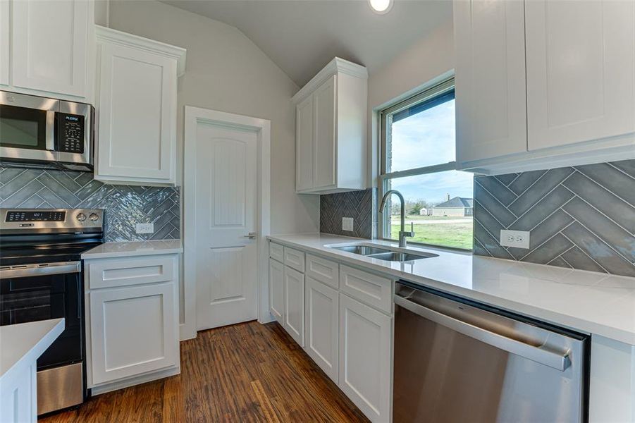 Kitchen featuring white cabinetry, sink, dark wood-type flooring, decorative backsplash, and appliances with stainless steel finishes