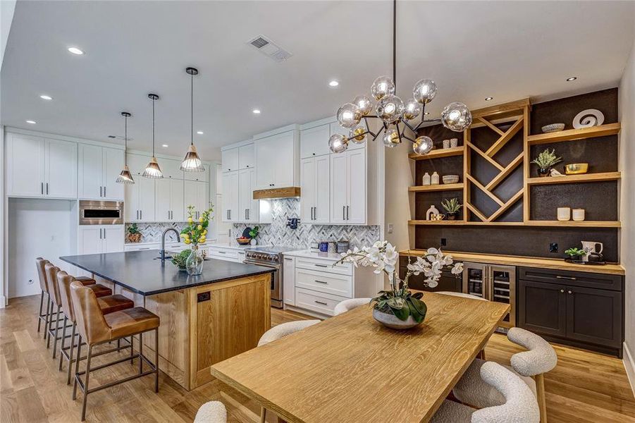 Kitchen featuring white cabinets, a kitchen island with sink, open shelves, tasteful backsplash, and recessed lighting