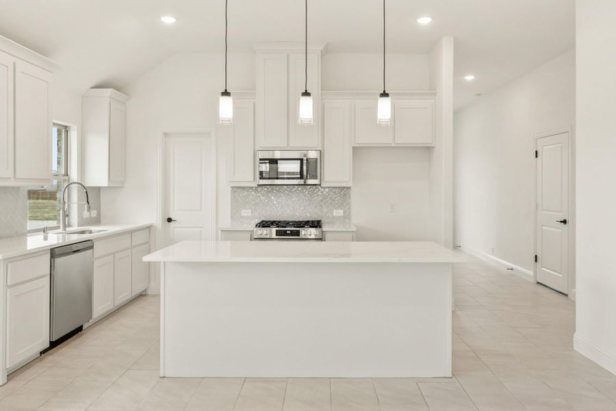 White kitchen with center island, pendant lights, stainless steel appliances, and tile backsplash