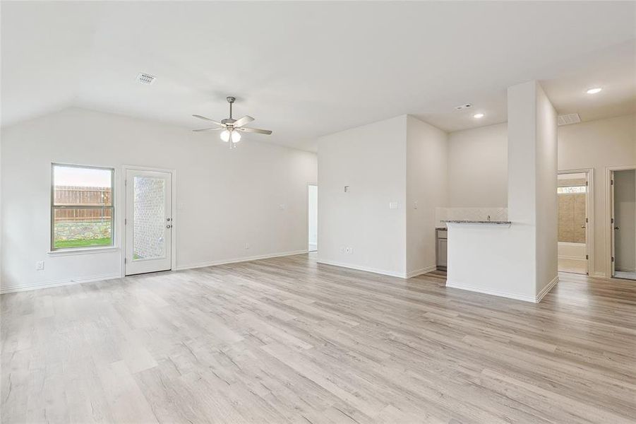 Unfurnished living room with vaulted ceiling, light hardwood / wood-style flooring, and ceiling fan