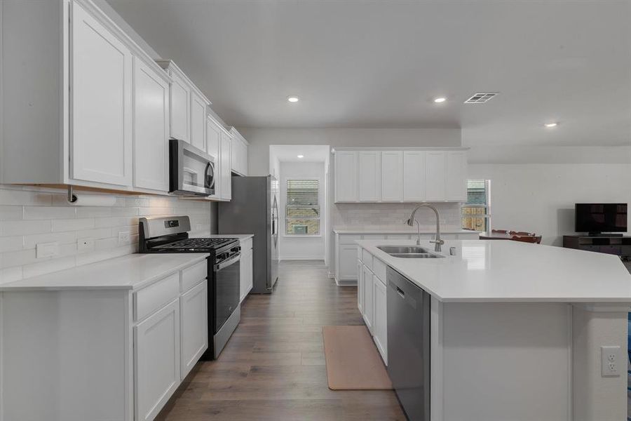 Kitchen featuring light countertops, appliances with stainless steel finishes, a sink, and a healthy amount of sunlight