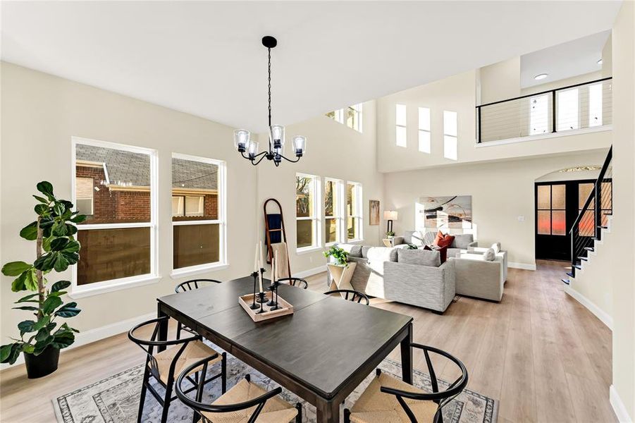 Dining area with a towering ceiling, light wood-type flooring, and a notable chandelier