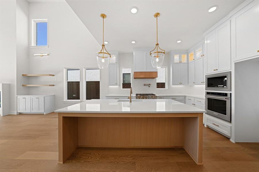 Kitchen with glass insert cabinets, oven, light wood finished floors, white cabinetry, and recessed lighting Kitchen with glass insert cabinets, oven, light wood finished floors, white cabinetry, and recessed lighting