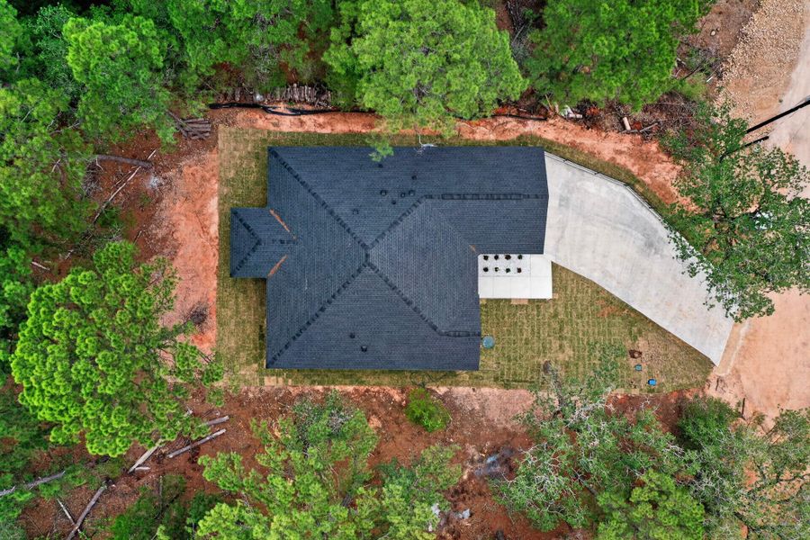 An aerial perspective reveals a newly constructed residence nestled amongst natural woodlands, featuring a clean roof and freshly laid sod. An aerial perspective reveals a newly constructed residence nestled amongst natural woodlands, featuring a clean roof and freshly laid sod.