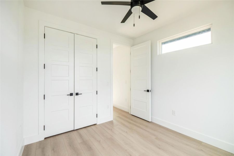 Unfurnished bedroom featuring light wood finished floors, a closet, and ceiling fan