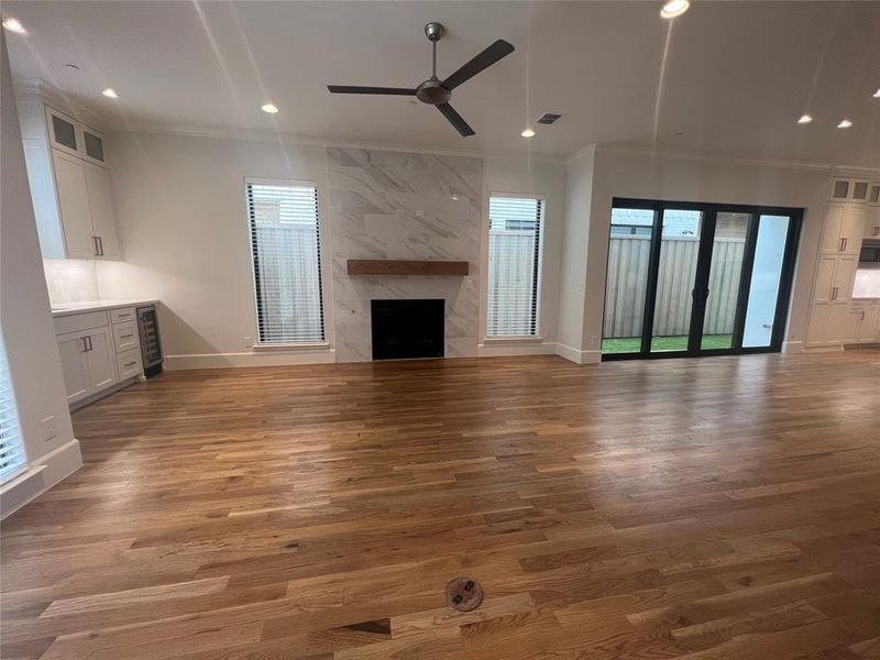 Unfurnished living room with ceiling fan, crown molding, hardwood / wood-style flooring, and a premium fireplace