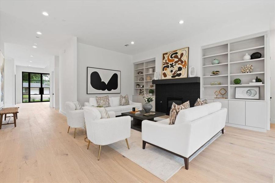 Living room with built in features, light wood-type flooring, and a brick fireplace