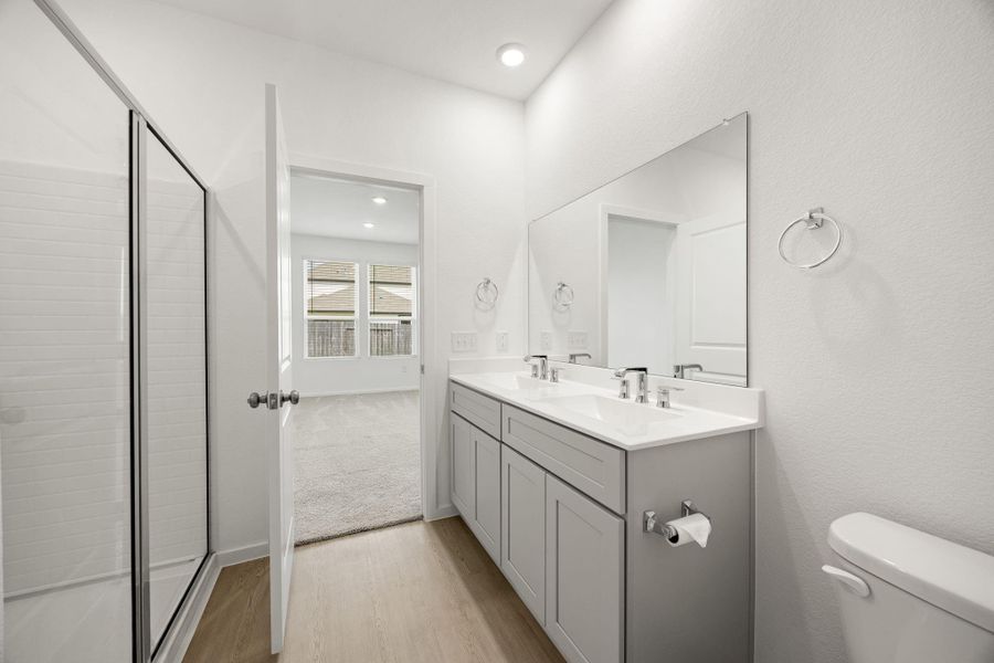 The primary bath combines thoughtful design and everyday convenience with a large vanity, private water closet, spacious shower, and direct access to the walk-in closet.