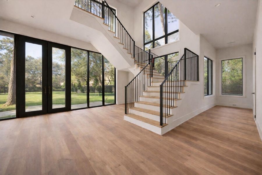 Rendering: Grand staircase entry featuring modern iron railings and expansive floor to ceiling windows that flood the space with natural light.