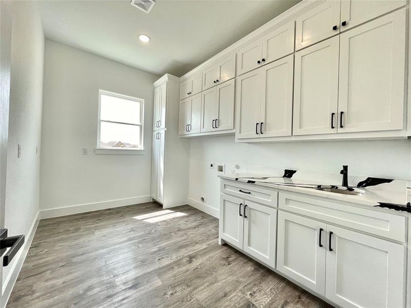Washroom with visible vents, baseboards, washer hookup, cabinet space, and electric dryer hookup Washroom with visible vents, baseboards, washer hookup, cabinet space, and electric dryer hookup