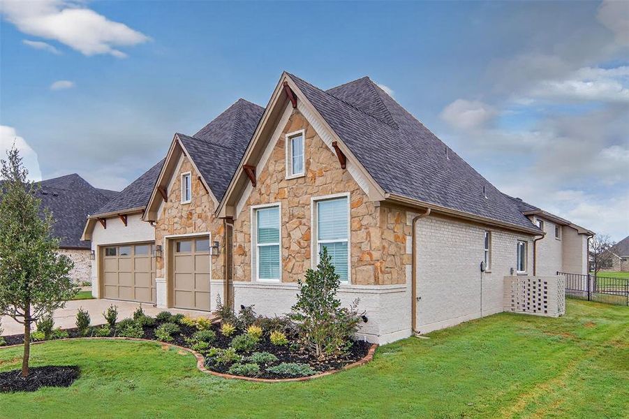 View of front of property featuring stone siding, an attached garage, and a shingled roof