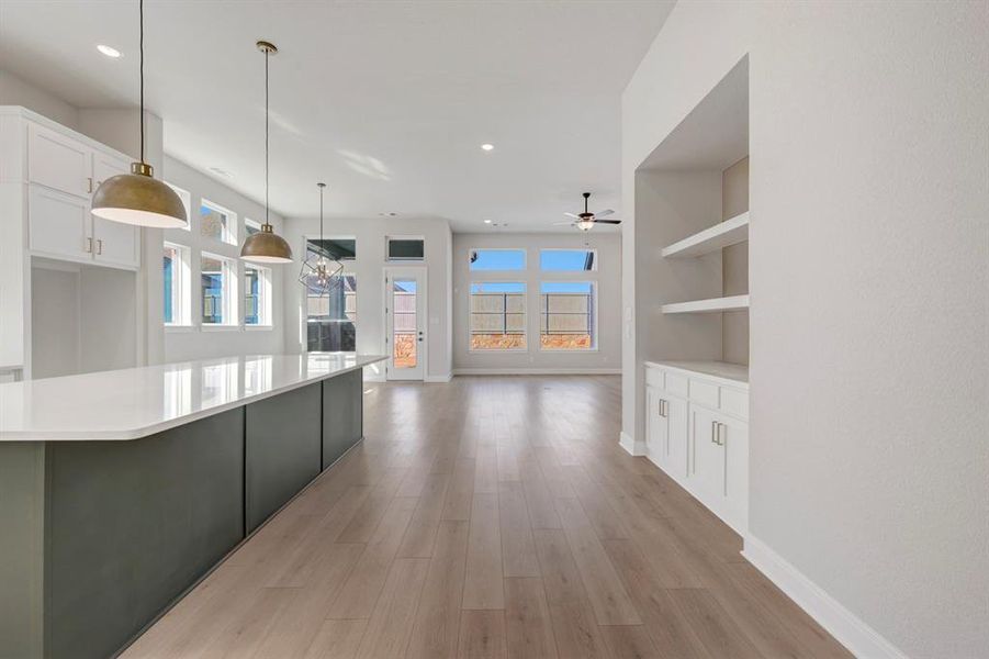 Kitchen featuring two tone color scheme, hanging light fixtures, open floor plan, light wood-style flooring, and plenty of natural light
