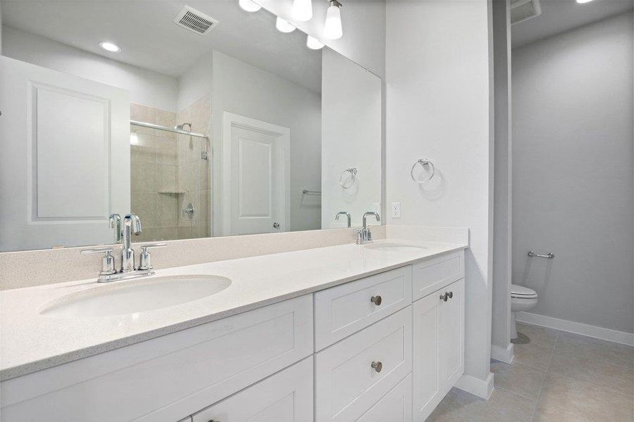 Bathroom featuring double vanity, a shower stall, recessed lighting, and light tile patterned floors
