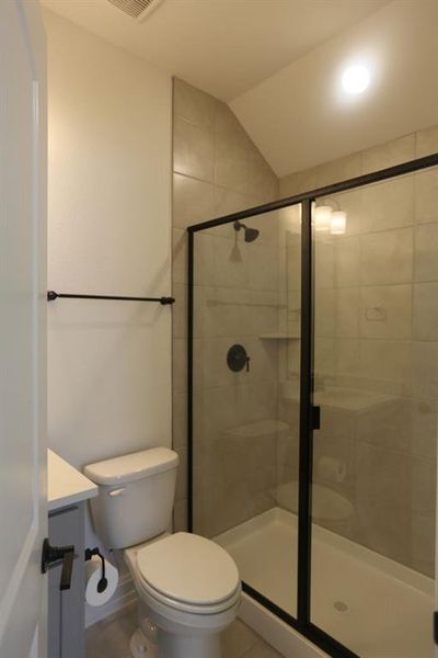 Spacious bathroom featuring a glass-enclosed shower with matte black fixtures and a built-in shelf
