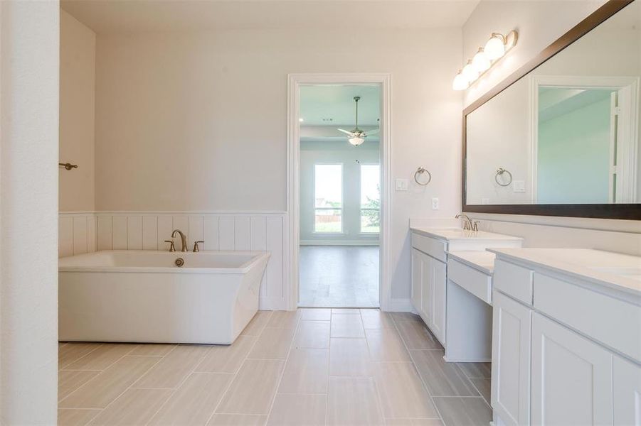 Bathroom with ceiling fan, a bathtub, double sink vanity, and tile patterned flooring