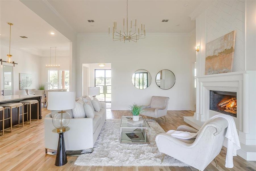 Living room featuring a towering ceiling, light hardwood / wood-style flooring, and crown molding