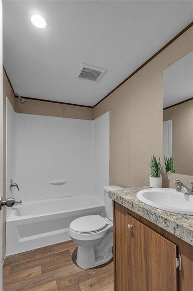 Full bathroom with toilet, vanity, shower / bathtub combination, and hardwood / wood-style floors