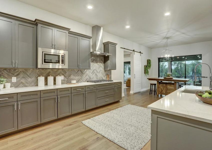 Staged kitchen with gray cabinetry and white countertops.