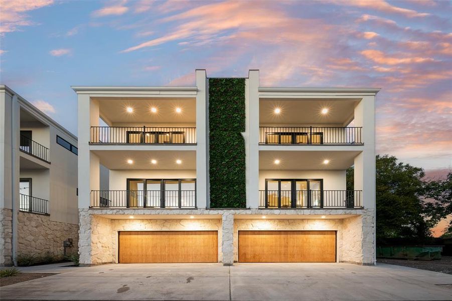 View of front facade featuring stucco siding, driveway, and stone siding