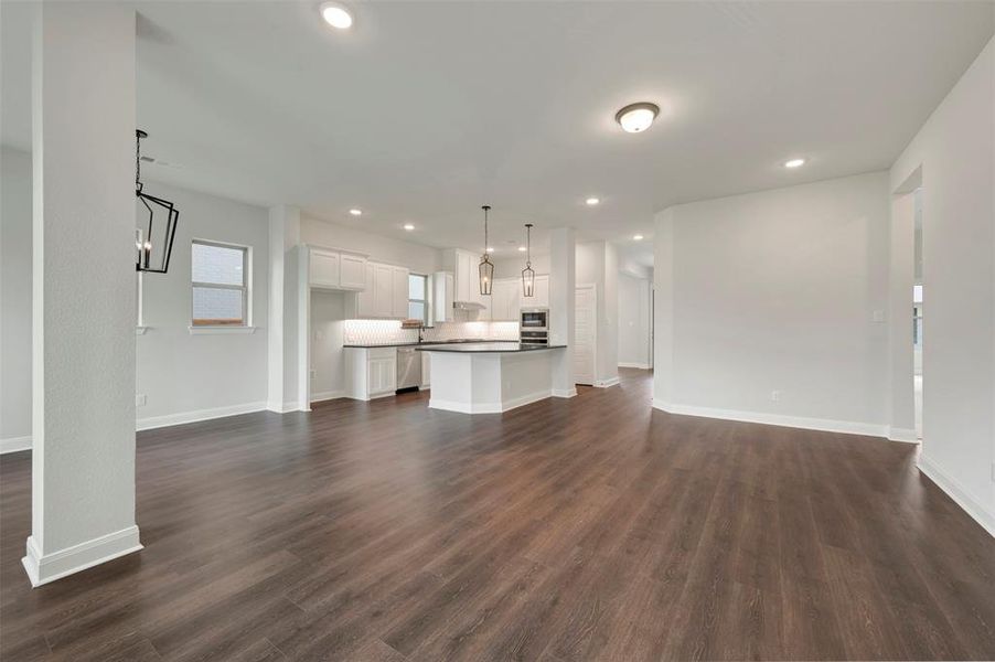 Unfurnished living room featuring dark wood-type flooring and recessed lighting