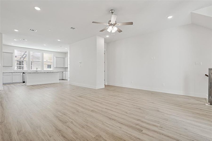 Open concept living space featuring light-toned flooring, white walls, and recessed lighting