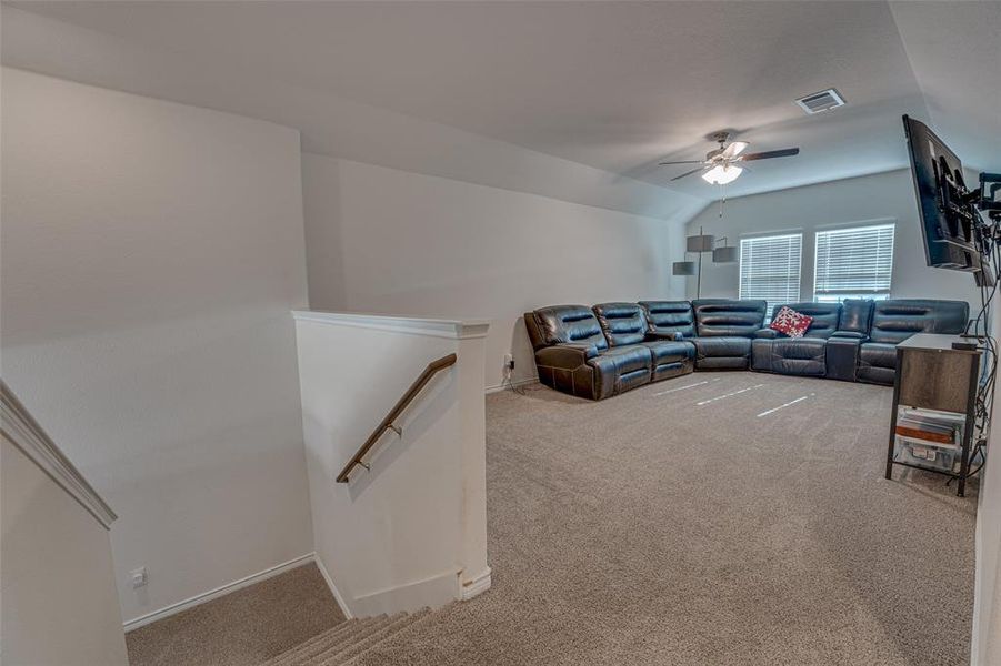 Living room featuring light carpet, vaulted ceiling, and ceiling fan