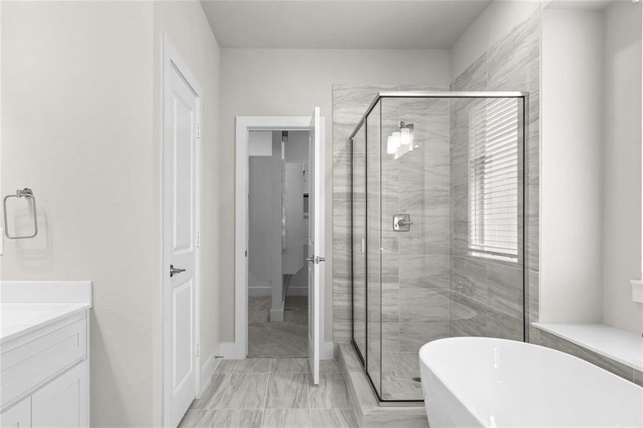 Modern bathroom featuring a freestanding soaking tub, glass-enclosed shower with tile surround, and a vanity with a white countertop Modern bathroom featuring a freestanding soaking tub, glass-enclosed shower with tile surround, and a vanity with a white countertop