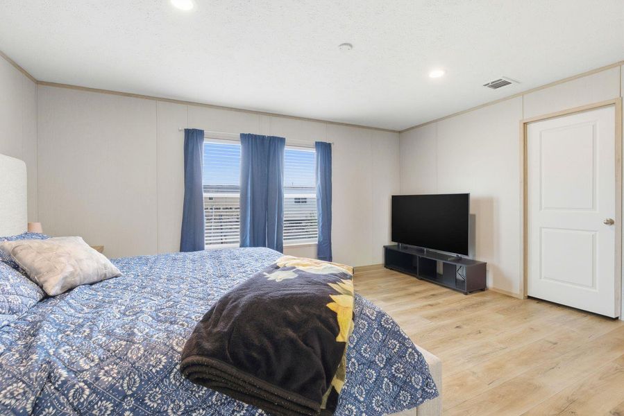 Bedroom with wood finished floors, recessed lighting, and ornamental molding