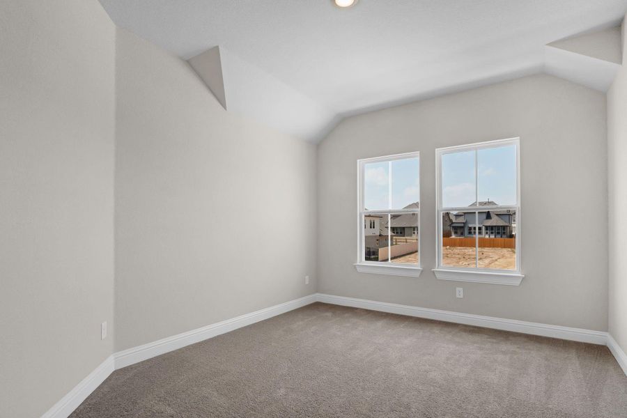 Empty room with lofted ceiling, baseboards, and carpet Empty room with lofted ceiling, baseboards, and carpet