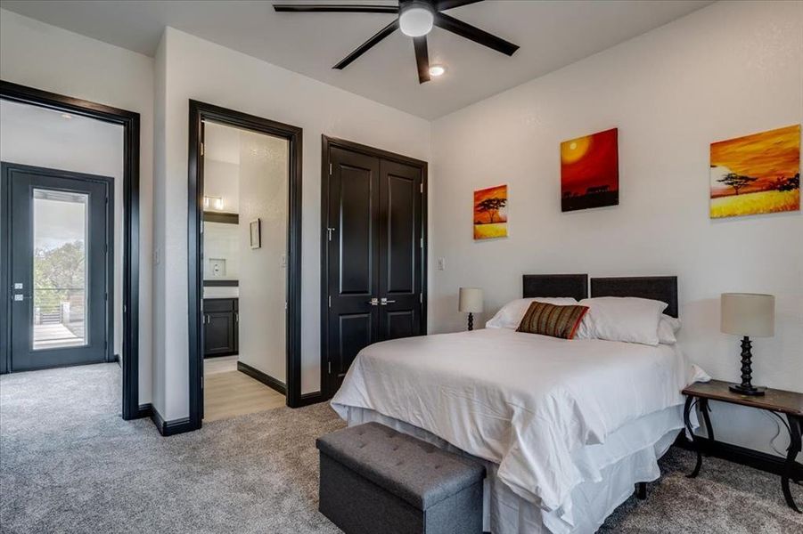 Bedroom featuring light colored carpet, ensuite bath, ceiling fan, and a closet