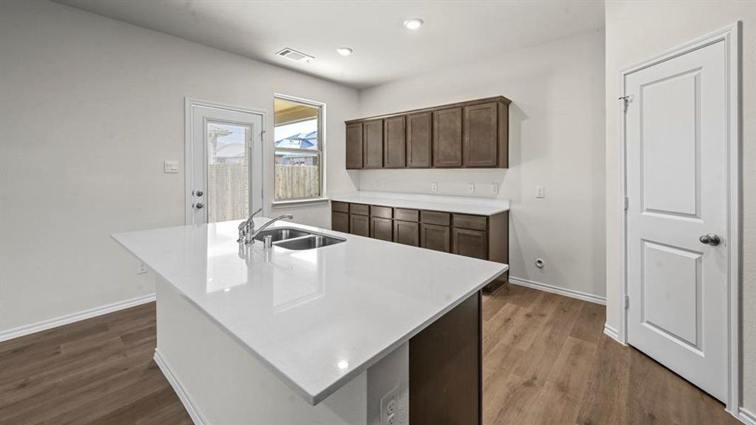 Kitchen island featuring a dual-basin stainless steel sink, chrome faucet, and white countertop