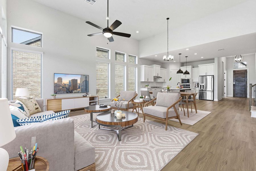 Living area featuring a high ceiling, hanging lights, light wood-type flooring, a ceiling fan, and healthy amount of natural light