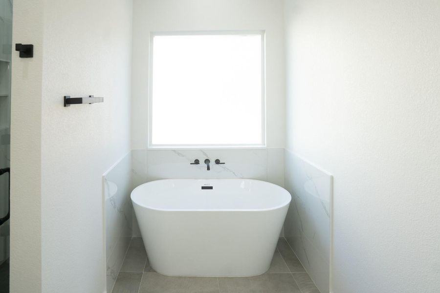 Full bath featuring a freestanding bath and light tile patterned floors