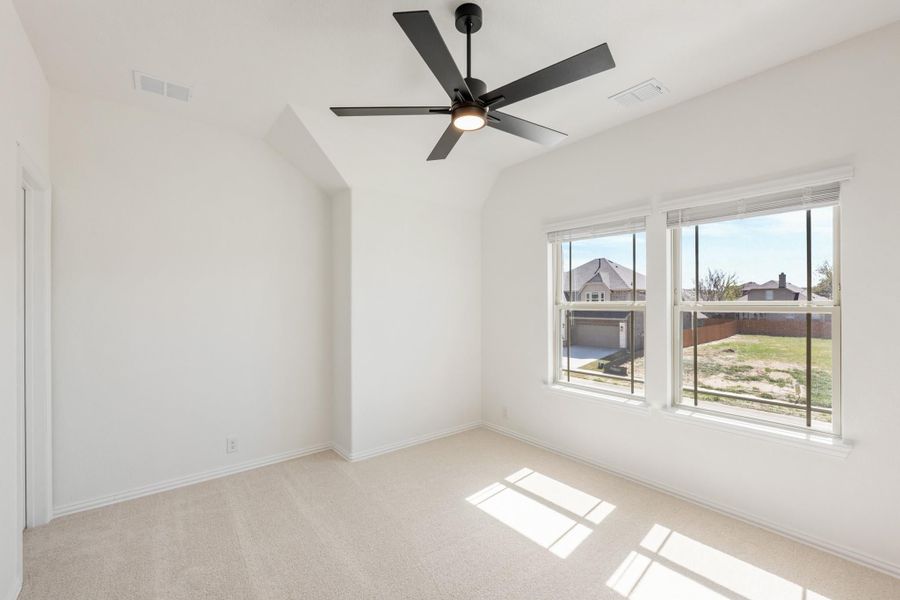 Empty bedroom with vaulted ceiling, black ceiling fan, carpet flooring, and two windows with neighborhood view