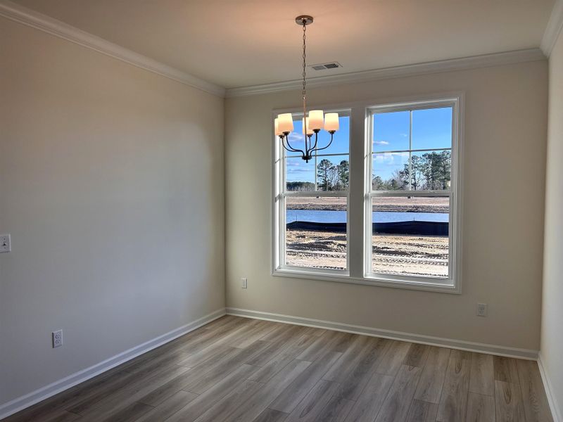 Unfurnished dining area with wood finished floors, ornamental molding, and a chandelier