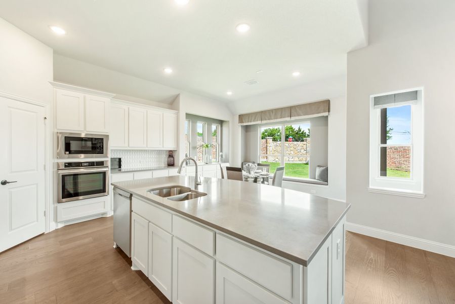 Kitchen with large center island, white cabinets, stainless steel appliances, and hardwood floors open to dining area. Kitchen with large center island, white cabinets, stainless steel appliances, and hardwood floors open to dining area.