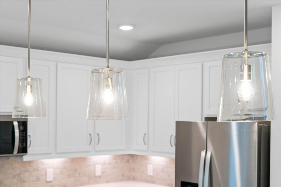 Three Clarion brushed nickel pendant lights that hang over the kitchen island.