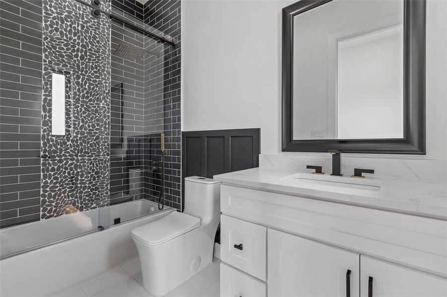 Full bathroom with tile flooring, combined bath / shower with glass door, toilet, and vanity with extensive cabinet space