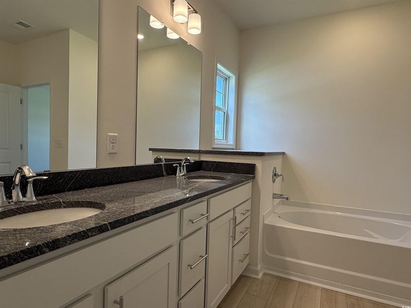 Bathroom with a stall shower, double vanity, and wood finished floors Bathroom with a stall shower, double vanity, and wood finished floors