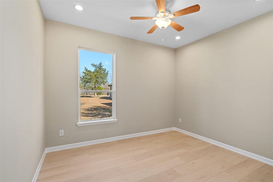 Cozy bedroom bathed in natural light with soft neutral walls and hardwood floors—ready for your personal touch.
