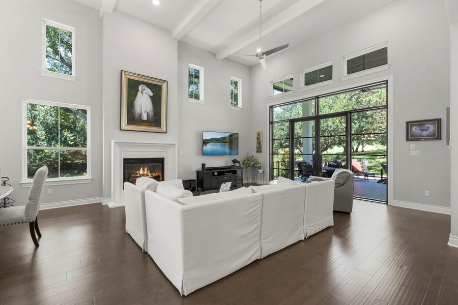 A grand living space with high ceilings and a fireplace, featuring large windows that invite the outdoors in.