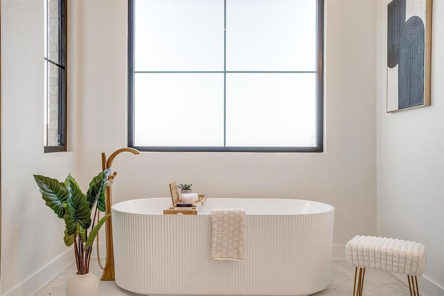 Bathroom featuring a soaking tub and baseboards
