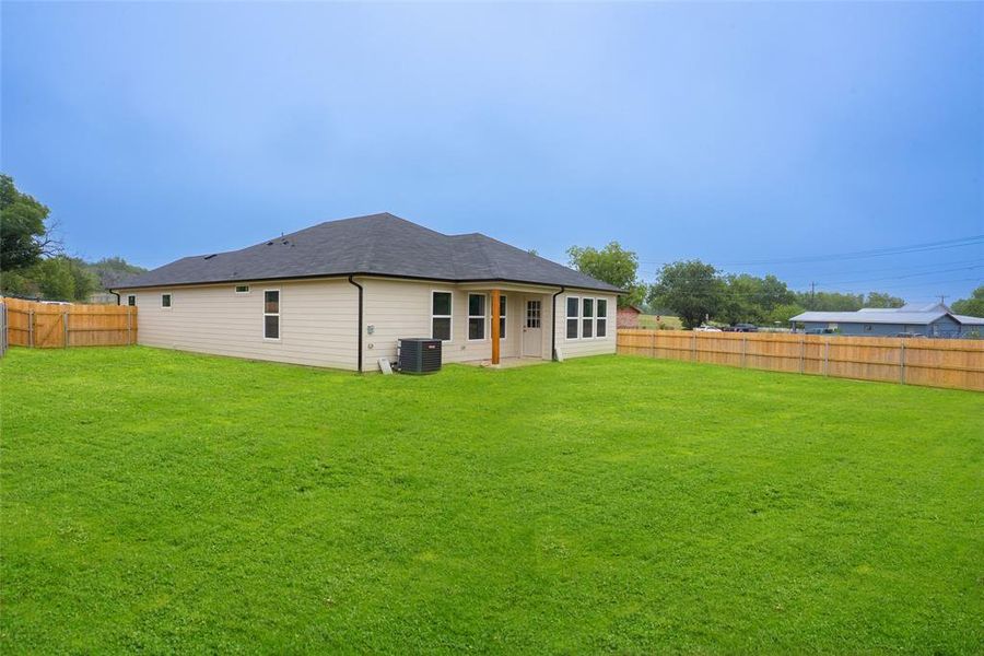 Rear view of property featuring a patio, a fenced backyard, and roof with shingles
