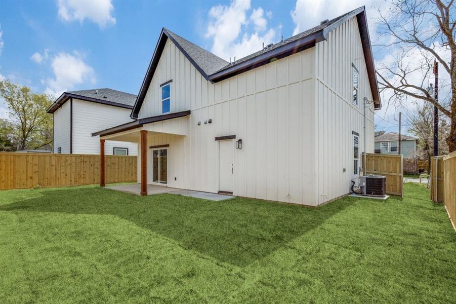 Rear view of property with a lawn, a patio, and central air condition unit